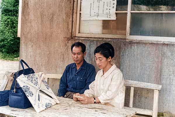岩洞湖畔の自宅の売店前でくつろぐ夫妻